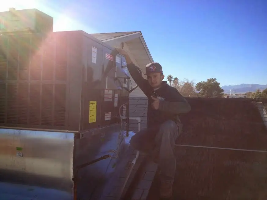 HVAC technician performing Air Duct Cleaning on a rooftop unit in Mack